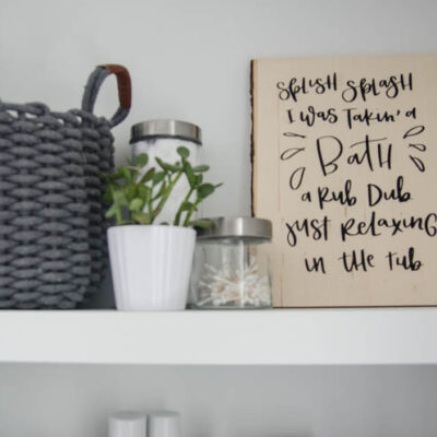 DIY Wood Sign for Bathroom. A wood Plank with black lettering (iron on vinyl) reads: Splish Splash I was takin' a bath. Rub dub just relaxing in the tub.