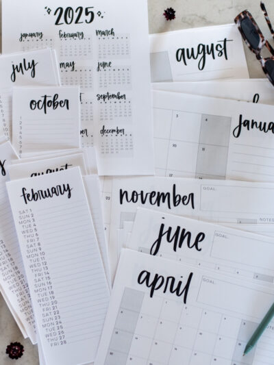 simple hand lettered collection of calendars including list calendars, perpetual calendars, monthly calendars, year at a glance calendar and large format calendars free printable for 2025, shown printed off on a marble countertop with green pen